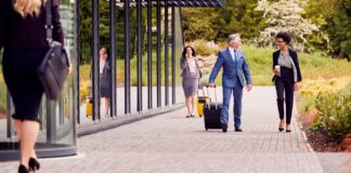 Is the C-suite practicing what they preach on business travel? group-of-business-delegates-with-luggage-arriving-2023-11-27-04-53-05-utc