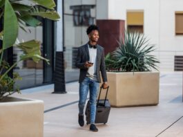 cheerful-black-businessman-with-suitcase-2023-11-27-04-50-16-utc